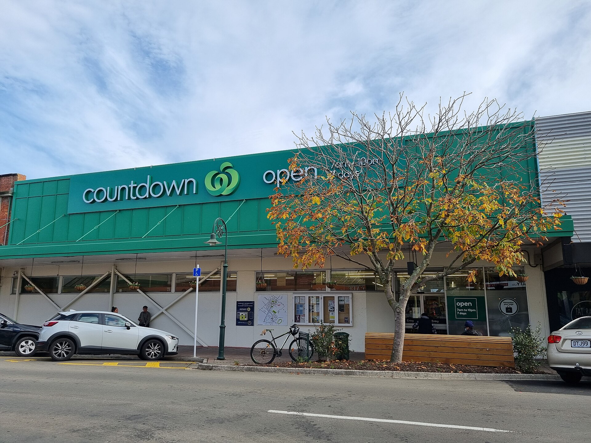 A Countdown supermarket building displays an 'open' sign amidst autumn trees, relating to the history of radio countdown.